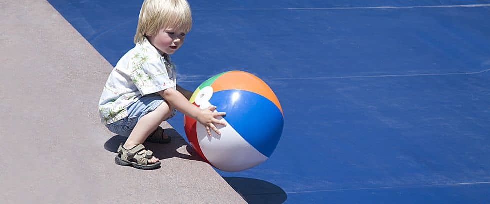 Young Child Picking A Ball From A Covered Pool